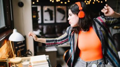 
		Young businesswoman dances with headphones
	